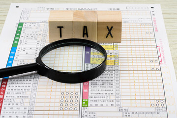 確定申告書と虫眼鏡で税務調査のイメージ