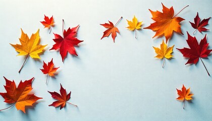 Autumn leaves in various colors scattered on a light blue background, maple leaves in shades of red and yellow
