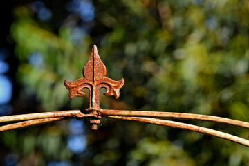 Ornamental arrow with side embellishments secure curved metal rods