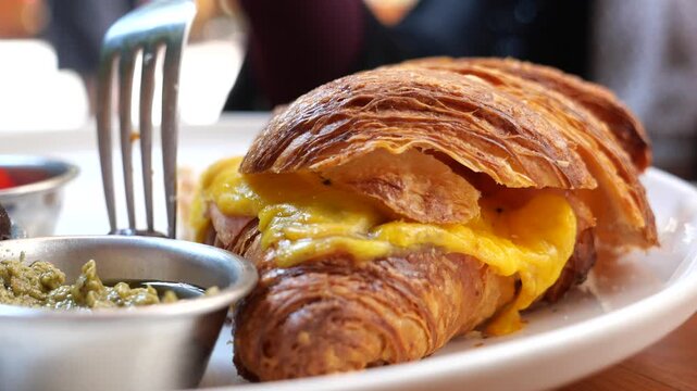 Enjoying a cheesy croissant sandwich at a cafe