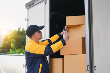 Delivery Person Loading Cardboard Boxes into Delivery Truck on a Bright Sunny Day