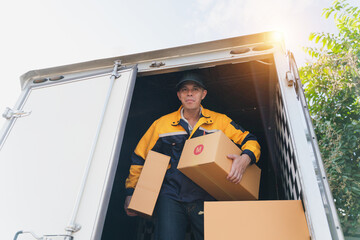 Delivery Person Unloading Boxes from Truck in Bright Daylight with Lush Green Background