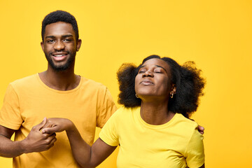 Obraz premium Joyful young African couple in matching yellow outfits, expressing love and happiness against a bright yellow background, perfect for seasonal celebrations