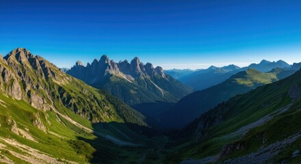 Fototapeta premium Panoramic vista rugged, jagged peaks rise above verdant valley, under a clear, bright blue sky