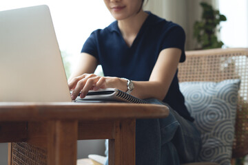 Asian business woman working with laptop computer, typing on keyboard, searching the information, remote working at cafe. Student studying online at coffee shop, e-learning