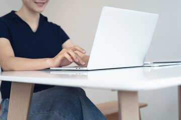 Happy young asian business woman sitting at office table working on digital tablet, surfing the internet at home office, closeup. Female interior designer using tablet
