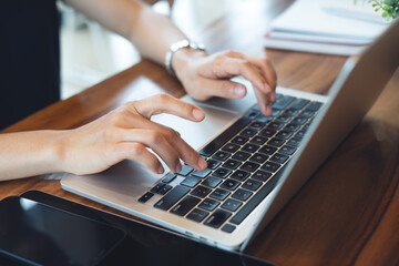 Business woman working on laptop computer with digital tablet and notebook on office table. Woman hands typing on laptop keyboard, remote working from home office, Student studying online class