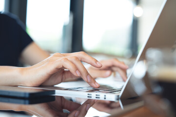 Close up of business woman hands typing on laptop keyboard at home office. Woman freelancer remote working, using laptop computer at coffee shop