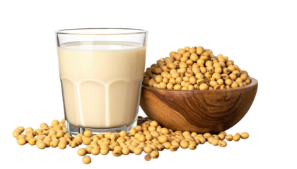 Glass of milky beverage beside a wooden bowl of light brown beans, on a surface