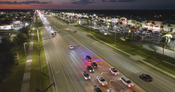 Police car with flashing lights pulled over a speeding vehicle at night on a busy city street in the USA. Urban traffic passing during traffic stop.