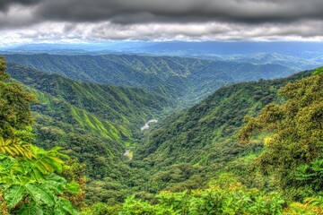 Fototapeta premium Lush valley nestled amongst steep, green mountains under a stormy sky