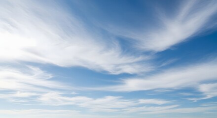 Wispy white cirrus clouds drift across a bright blue summer sky on a clear day.