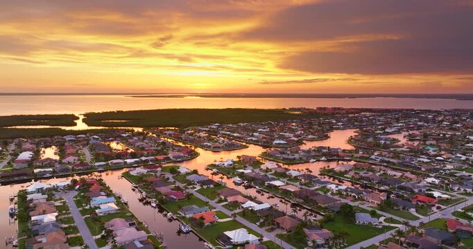 Sunset aerial panorama of Florida Gulf waterfront. Wealthy neighborhood with elegant houses, premium living and palm-lined canals.
