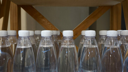 Bottled water on wooden shelf, transparent plastic bottles with white caps