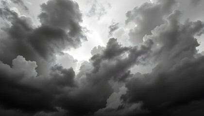 Dramatic monochrome image of a sky filled with dark, ominous storm clouds, with a small patch of light breaking through.