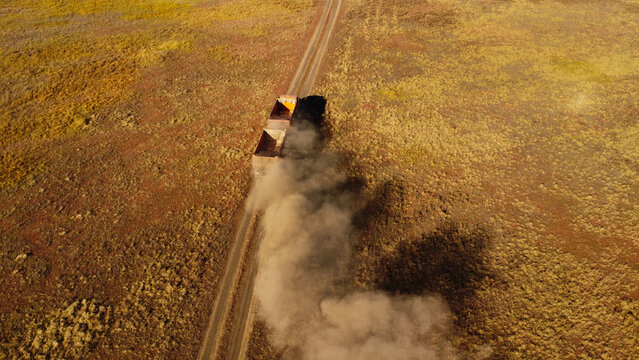 Aerial View of Heavy Haul Trucks Driving on Dirt Road Kicking up Dust