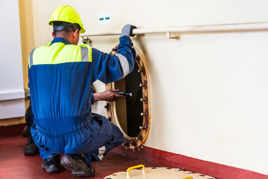 Crew member near a narrow hatch after providing first aid during a man evacuation drill from a confined space on a merchant ship.