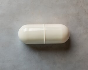 A single white capsule pill isolated on a grey textured background