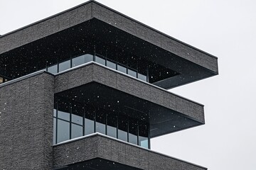 Fototapeta premium Modern, dark gray building with layered, geometric balconies and windows