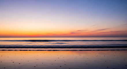 A serene seascape captures the tranquil ocean waves under a vibrant sunset sky.