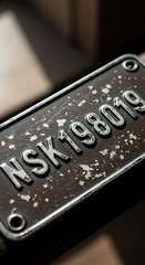 Close-up of a weathered metal plate with embossed NSK198019 text.