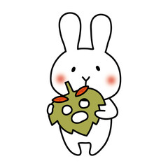 落ち葉のお面を持つ白いうさぎ