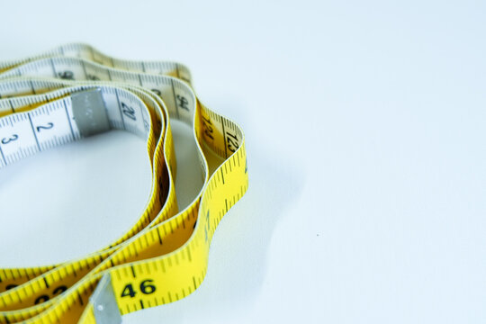 Yellow measuring tape rolled on white background, close-up tool for tailoring and measurement. - Powered by Adobe