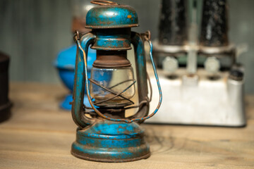 Old iron and oil lamp displayed on a wooden table, surrounded by a stove and a light bulb. This...