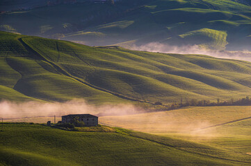 Obraz premium spring sunrise over the Tuscany hills with a farm house inside the valley, Italy