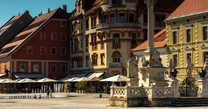 Maribor, Slovenia - August 9, 2025: A timelapse of Maribor&rsquo;s central square (Glavni trg), showing historic facades, the Plague Column, and people walking under bright summer sunlight.