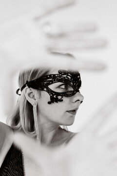 Woman wearing ornate black lace masquerade mask, black and white