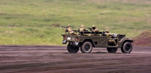 Equipped with rifles, the uniformed personnel are alert, traversing rugged ground in their robust tactical transport vehicle with speed and purpose.
