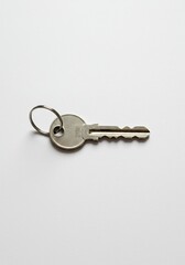 A solitary, simple house key lies on a clean, uncluttered white surface, symbolizing everyday isolation and personal space. (132 characters) ,symbol ,object ,close up