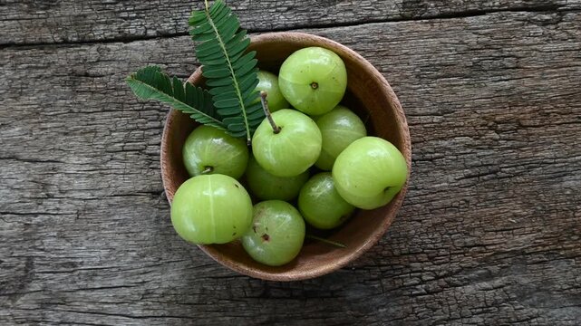 Fresh Amla (Indian gooseberry, Phyllanthus emblica) fruits with leaf on wooden background. herbal medicine plant