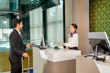 Attractive young woman will receiving a passport and ticket from businessman at airport check-in counter