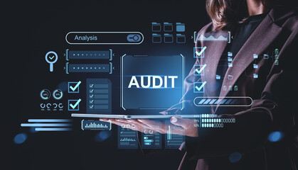 Businesswoman holding tablet with holographic audit interface and data analysis elements for financial control concept on dark background..