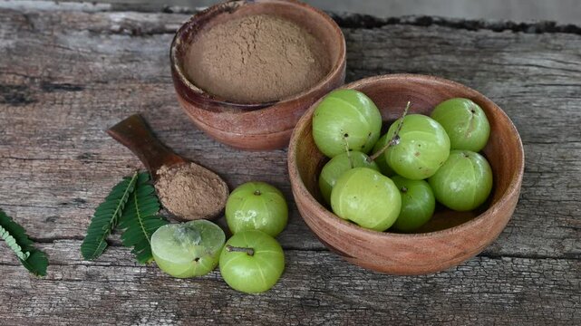 Fresh Amla (Indian gooseberry, Phyllanthus emblica) fruits with leaf on wooden background. herbal medicine plant