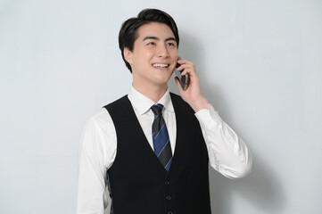 スマホで通話をするベストを着た日本人男性