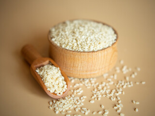 sesame seeds in a wooden bowl on a beige background
