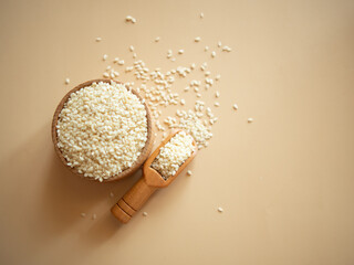 sesame seeds in a wooden bowl on a beige background