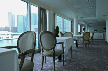Formal and elegant ocean view a la carte dining room restaurant onboard luxury cruiseship or cruise ship liner with set tables in Country Club interior design style and ceiling ambient lighting