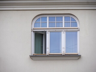 Close-up of a large arched window with white frames on a light-colored building facade