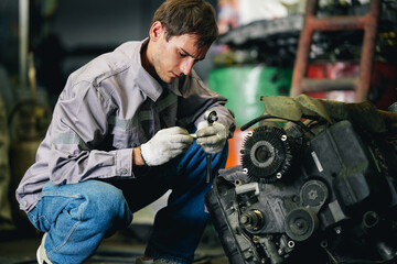 White man technician checking used car damaged engine block at scrap yard warehouse recycle area...