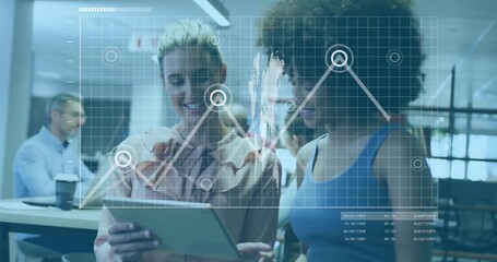 Reviewing two coworkers viewing tablet screen in open office, with laptop coffee cup chart overlay