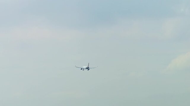 Airplane landing on runway with city skyline in background on a foggy day in Mumbai, India. Wide view of urban buildings, airport activity, and incoming aircraft
