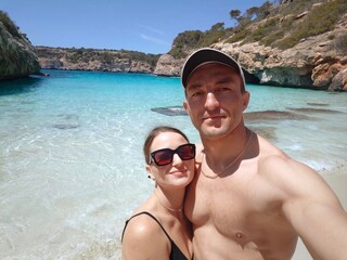 young couple on the beach. Calo del Moro, Mallorca, Spain. Happy young couple taking a selfie on a remote beach with turquoise water. Beach with blue transparent water. Romantic Summer vacation couple
