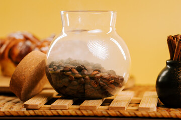 Coffee beans in a glass jar on a wooden tray with cinnamon sticks