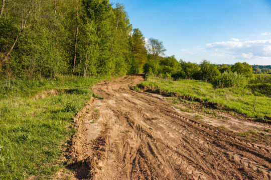 Rough-and-tumble dirt road meanders through verdant woods, a winding path less traveled under a bright blue sky, calling for adventure - Powered by Adobe
