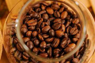 Rich brown coffee beans in a glass jar on a wooden table in a cozy kitchen setting