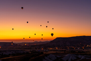 Hot air balloon flying over rocky landscape at sunrise in Cappadocia. Turkey